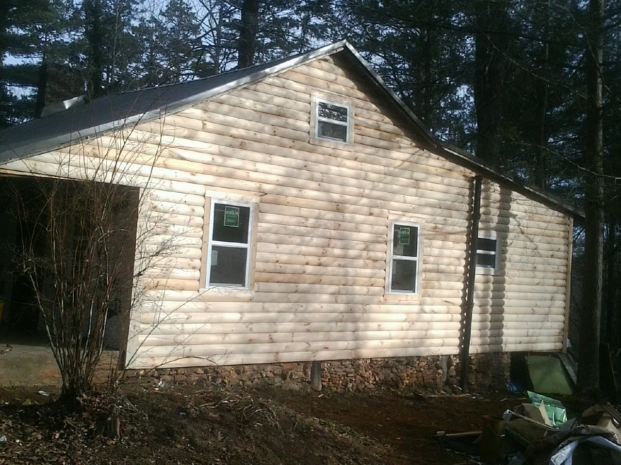 New log siding and dark metal roofing on a gable end in Canby