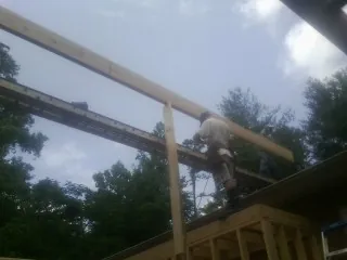 Carpenter setting a ridge beam over a new addition frame — Ice Dam Removal by Roofing Brothers in Canby