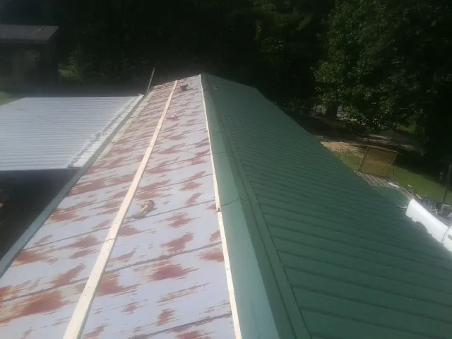Old rusted panels beside newly installed green metal roofing — Wind Damage Roof Repair by Roofing Brothers in Canby