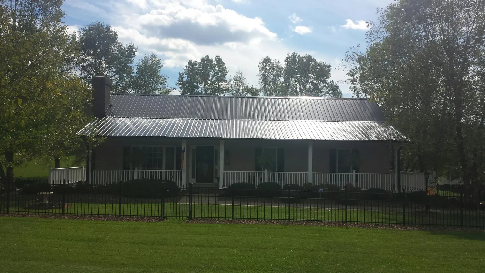 Gray metal roof on a brick ranch with a full width front porch — Gutter Guard Installation work by our crew in Canby