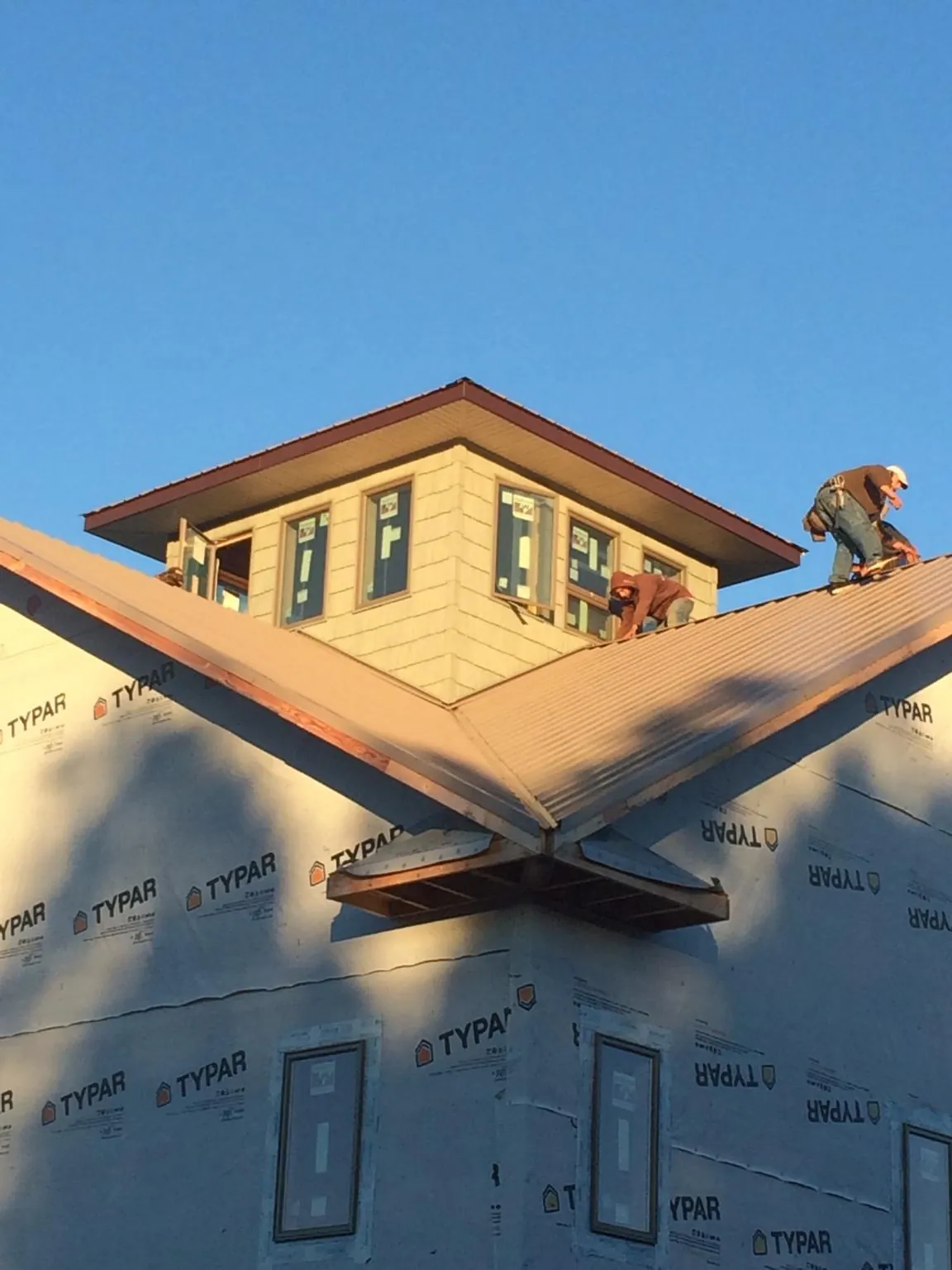 Roofers working around a rooftop cupola on a new metal roof at sunset — Roof Waterproofing in Canby by Roofing Brothers